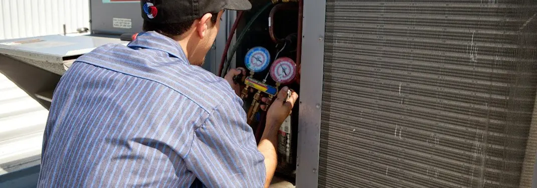 HVAC technician servicing a condenser unit in Great Neck